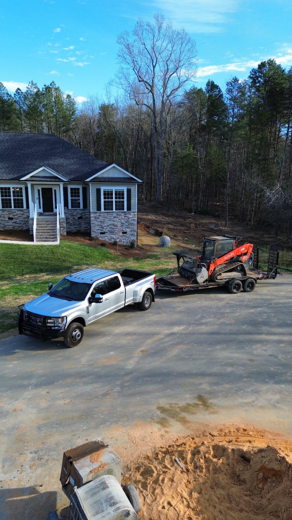 Aerial view of truck, trailer, and track loader mulcher at a residential job site